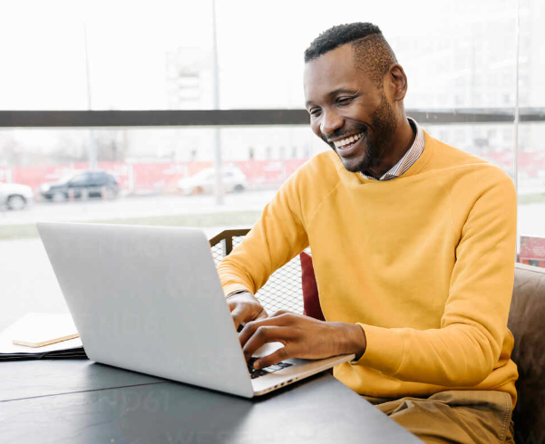 Older Black male smiling with laptop 